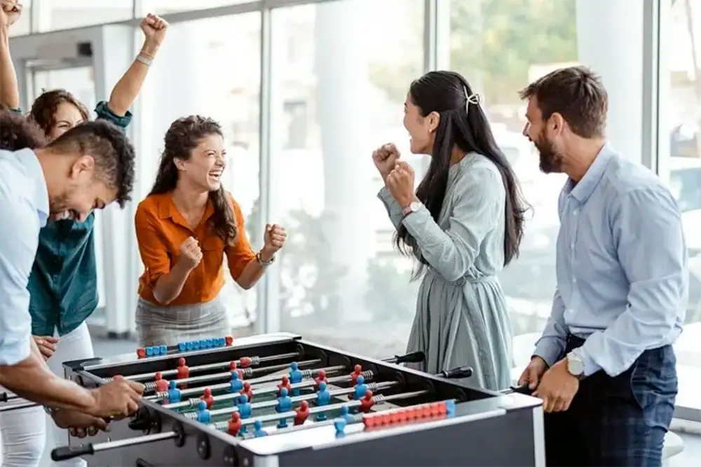 Uber cool happy office workers playing foosball